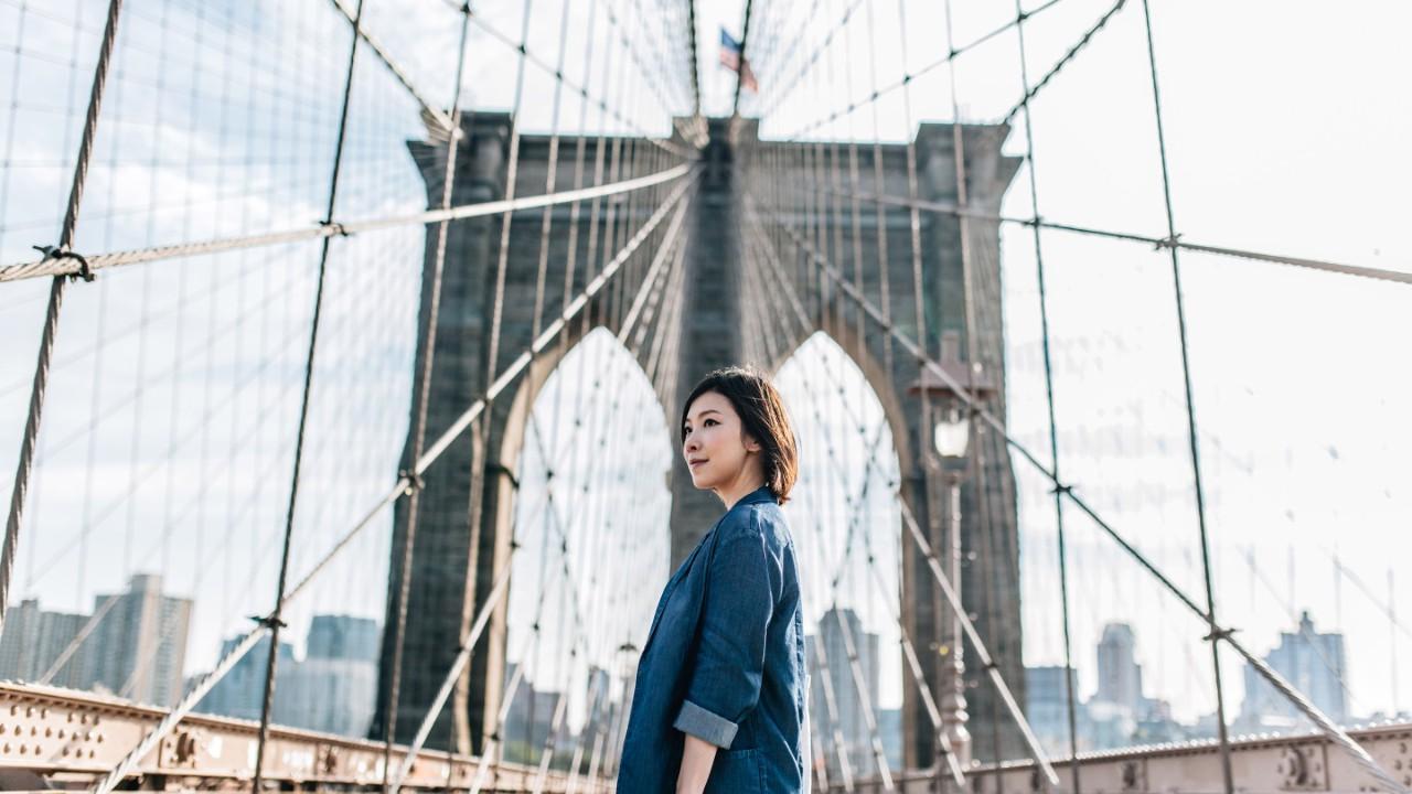年轻的女商人仰望布鲁克林大桥，俯瞰纽约的市容